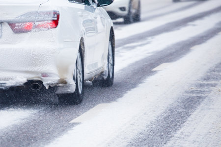 white snow-covered car drives along a snow-covered road at winter day.の写真素材