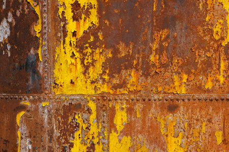 beautifully rusted rivetted sheet metal with leftovers of yellow paint texture and full-frame backgroundの写真素材