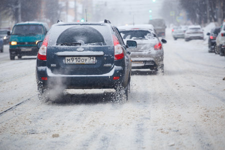 cars driving along snow covered road at winter dayのeditorial素材