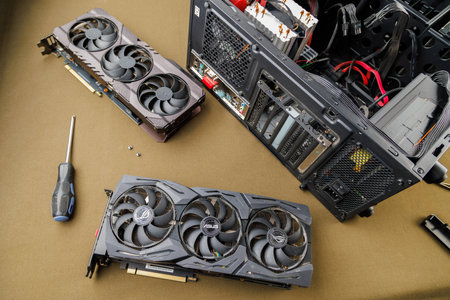 graphics card upgrading concept, two gaming graphics cards near desktop miditower ATX pc case on tan...