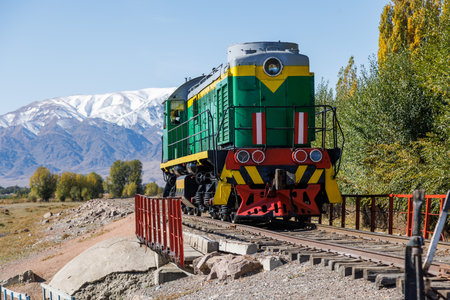 green diesel locomotive crossing small bridge at summer day in Balykchy, Kyrgyzstanの写真素材