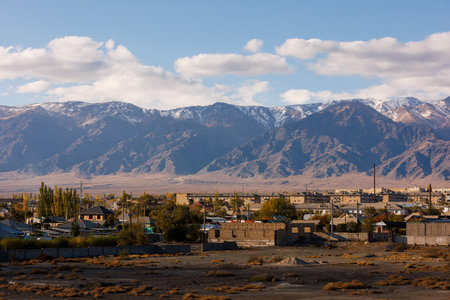 Small Kyrgyz town Balykchy cityscape in front of massive mountain ridgeの写真素材