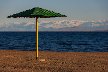 rigid steel umbrella on beach of mountain lake at sunny eveningの写真素材