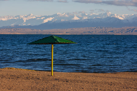 rigid steel umbrella on beach of mountain lake at sunny eveningの写真素材