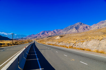 empty highway road with separating concrete barrier in mountains at sunny autumn dayの写真素材
