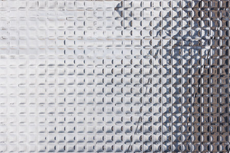 Closeup full-frame background and texture of aluminum coated butil rubber sheet with square pattern.の写真素材