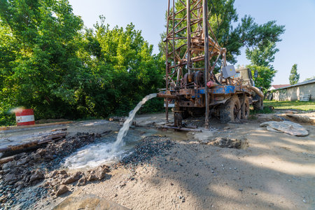 old water pump truck extracts water from a hole in the ground at sunny summer dayの写真素材