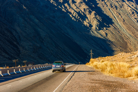 Car is driving along the road to Issyk-Kul lake through natural Kyrgyzstan mountain landscape with concrete barrier.のeditorial素材