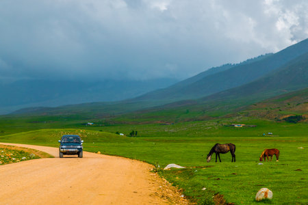 old SUV driving along dry dirt road in Semenovskoye gorge, Kyrgyzstanのeditorial素材