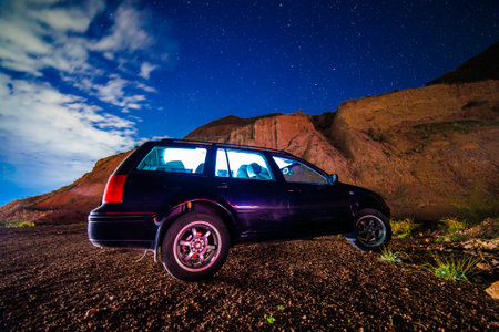 old black car at starry summer night in the desertの写真素材