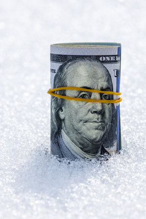 Roll of dollar banknotes on the snow surfaceの写真素材