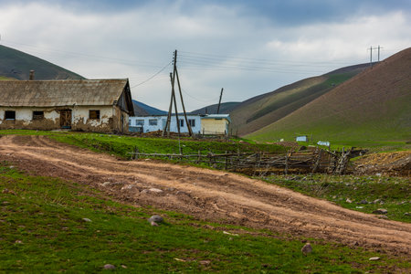 serene countryside landscape with rustic buildings, fence and foothills in the backgroundの写真素材