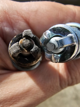 old and new spark plugs ends in a hand