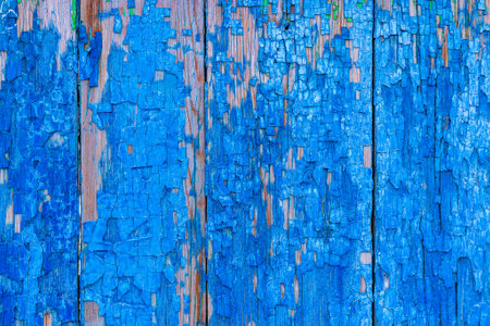 Vertical wooden planks with heavily peeling and cracked bright blue paint, revealing the bare wood underneathの写真素材