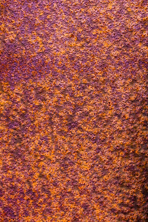 Metal surface with a thick layer of rust, exhibiting a predominantly orange hue with hints of purple and a rough textureの写真素材