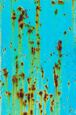 Extreme close-up of a turquoise metal surface with extensive rust formation and streaks down from...