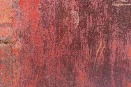 Worn red painted surface with scratches and discoloration, showing signs of age and use - Full-frame background and texture.の写真素材