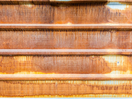 A close-up shows corrugated metal siding with significant rust patches over a faded zinc coated base. Protective galvanic coating failed.の写真素材