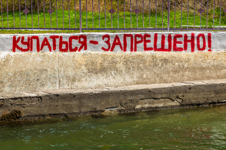 Concrete wall above water with warning message swimming is prohibited in russian.の写真素材