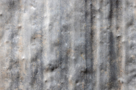 Weathered aluminum surface exhibits unique texture with visible dents and scratches. Industrial setting under bright daylight conveys a grungy, aged aesthetic.の写真素材