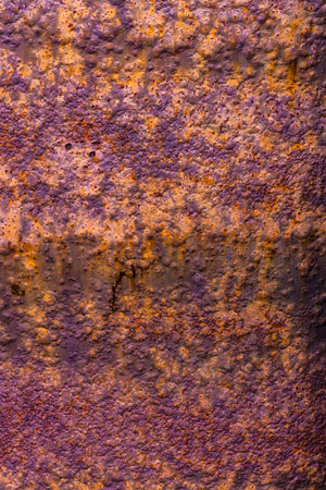 Metal surface with a thick layer of rust, exhibiting a predominantly purple hue with hints of orange and a rough textureの写真素材