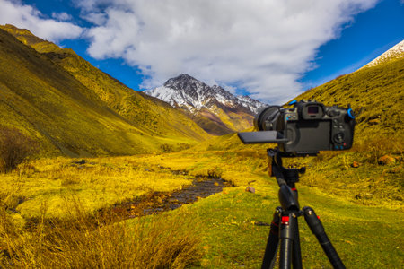Camera and stream in serene mountain valley landscapeの写真素材