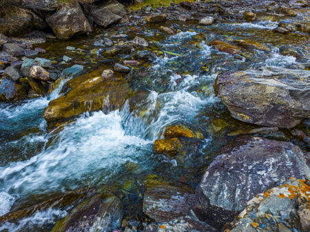 Cascading mountain stream flowing over colorful rocks in Kyrgyzstanの写真素材