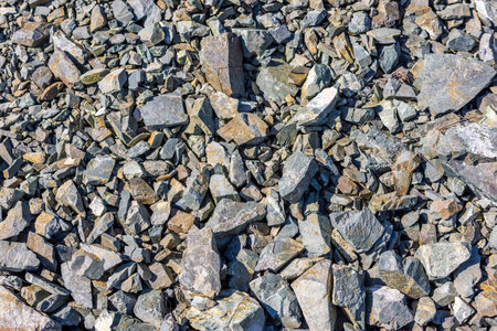 Pile of various gray and brown natural rocks and stones under bright sunlight - full-frame...