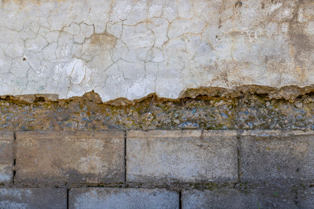 Weathered plastered and brick wall showing damage under sun lightの写真素材