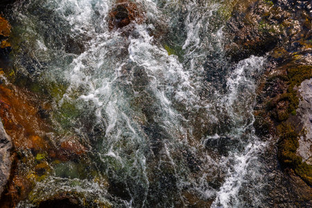 Flowing river with submerged rocks in natural setting, high angle viewの写真素材