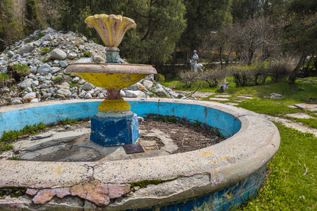 Dilapidated stone fountain in overgrown park garden in Kyrgyzstanの写真素材