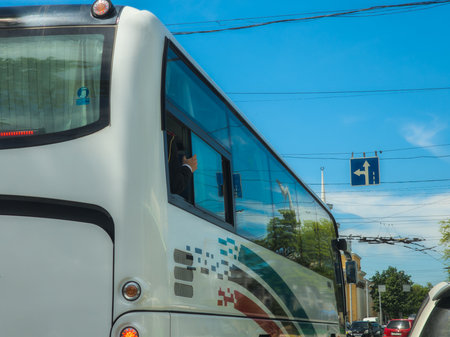 Bishkek, Kyrgyzstan - May 7, 2024 - man holding on to bus window frame on city street, daytimeのeditorial素材