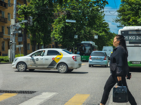 Bishkek, Kyrgyzstan - May 7, 2024 - Asian woman walking across city street during daytimeのeditorial素材