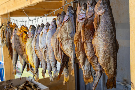 Dried fish hanging at rustic outdoor market stall during daytimeの写真素材