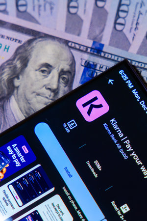 Balykchy, Kyrgyzstan - December 29, 2025 - Cellphone with Klarna app in Google play over dollar banknotesのeditorial素材