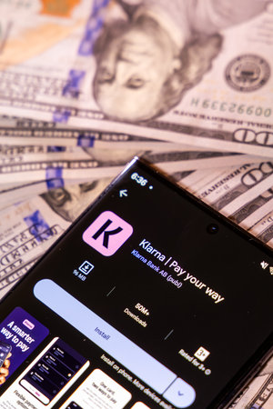 Balykchy, Kyrgyzstan - December 29, 2025 - Cellphone with Klarna app on hundred US dollar banknotes
