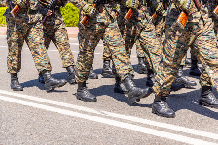 Military personnel marching in formation on paved road