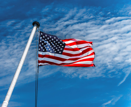 American flag flying against a blue sky.の写真素材