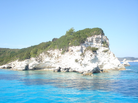 Cliff overlooking the crystal clear waters of a bay in Antipaxos resort in North Western Greeceの写真素材