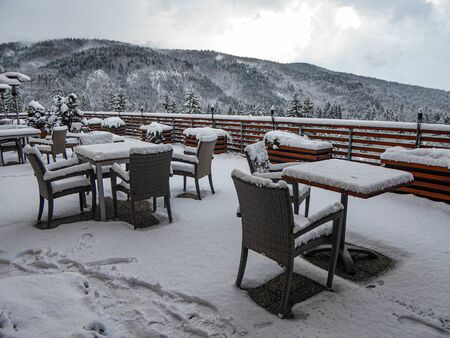 snowy summer terrace with tables and chairs in the mountains in a snowy landscapeの写真素材