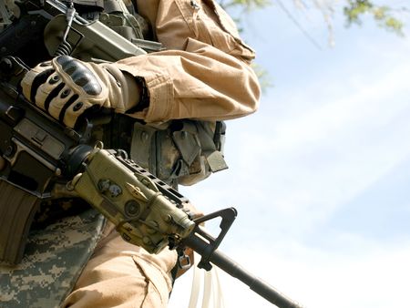 US soldier in camouflage uniform holding his rifle