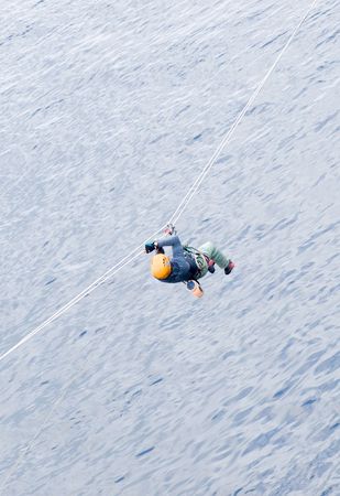 A male climber crosses a river via tyrolean traverseの写真素材