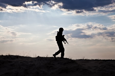 Silhouette of young soldier in military helmet against the sunの写真素材