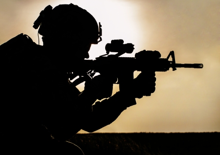 Silhouette of young soldier in military helmet against the sunの写真素材