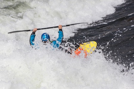 an active male kayaker rolling and surfing in rough waterの写真素材