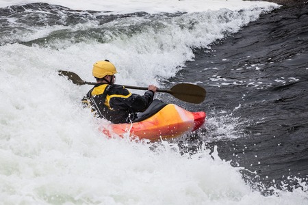 an active male kayaker rolling and surfing in rough waterの写真素材