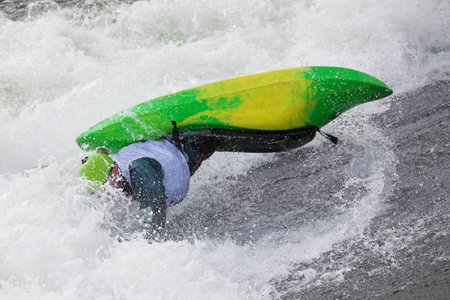an active male kayaker rolling and surfing in rough waterの写真素材