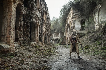 Nuclear post-apocalypse. Sole survivor in tatters and gas mask on the ruins of the destroyed cityの写真素材