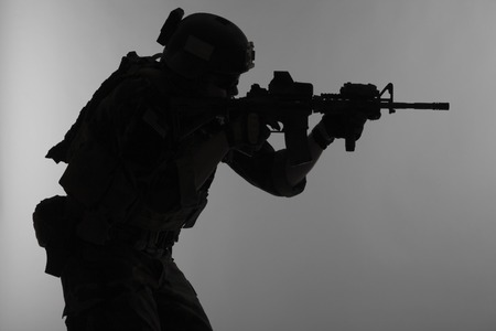 United states Marine Corps special operations command Marsoc raider with weapon aiming a gun. Silhouette of Marine Special Operator gray backgroundの写真素材