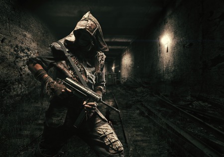 Nuclear post apocalypse. Underground life after doomsday in abandoned subway tunnels. Grimy survivor with homemade weaponsの写真素材